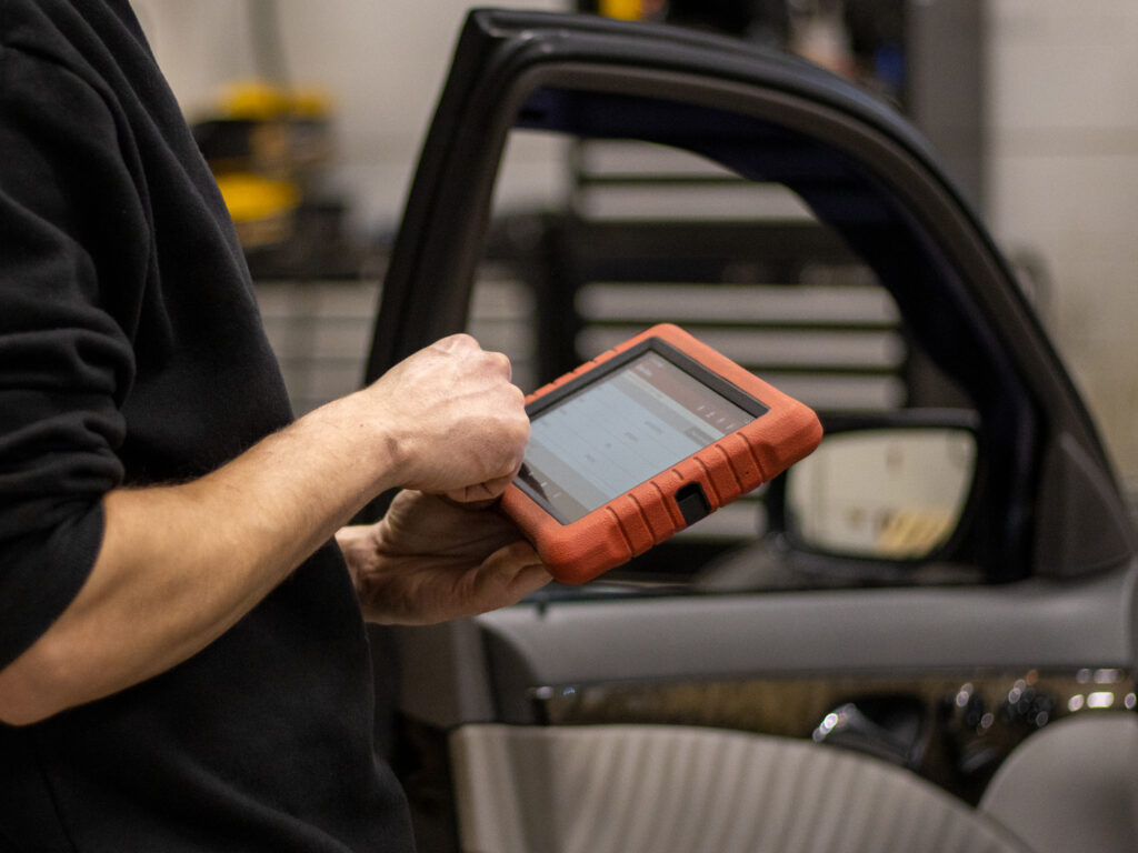 Autonasentaja lukemassa auton vikakoodeja vikakoodienlukulaitteella.