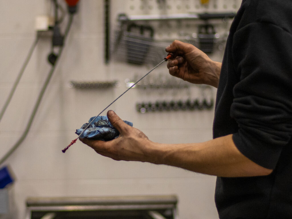 Autonasentaja tarkastamassa moottoriöljyntasoa auton öljytikusta.