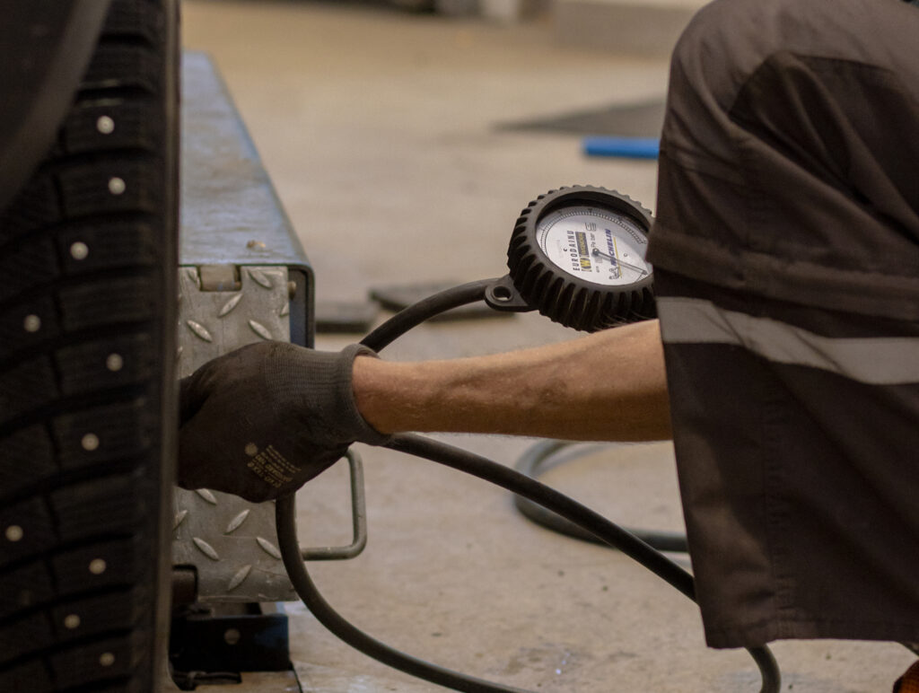 Autonasentaja tarkastaa auton rengaspaineita rengaspainemittarilla.