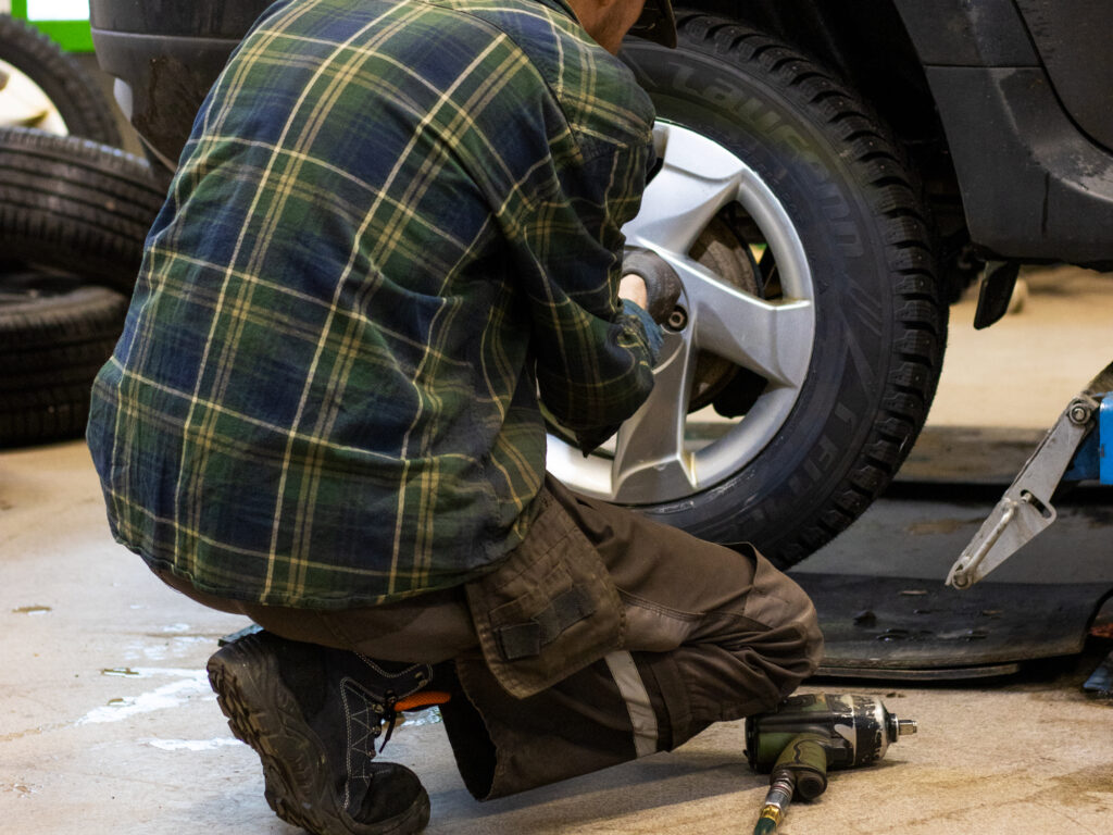 Autonasentaja vaihtamassa renkaita AT-Osan huoltohallissa.
